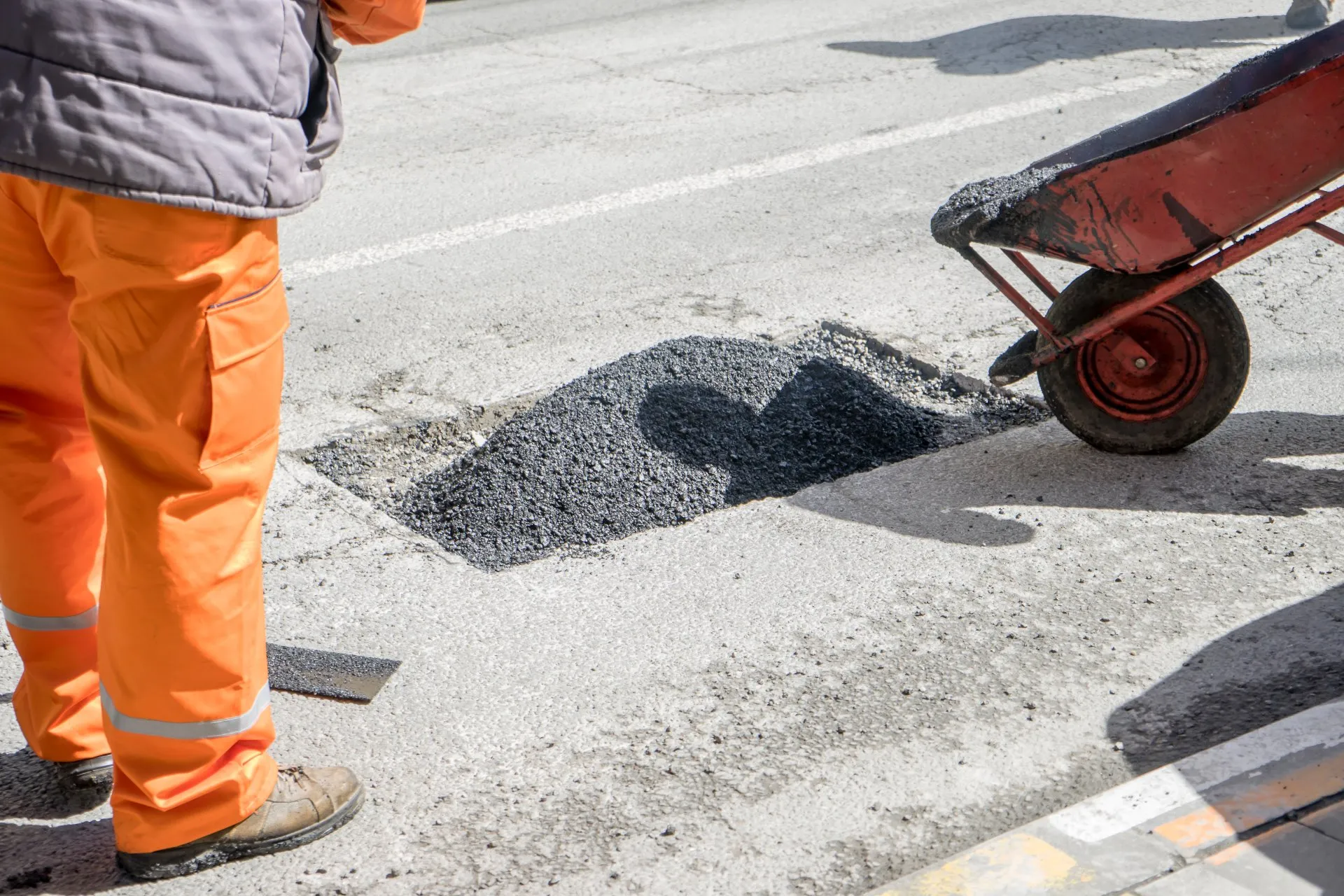 asphalt worker cutting asphalt road for a hot patch